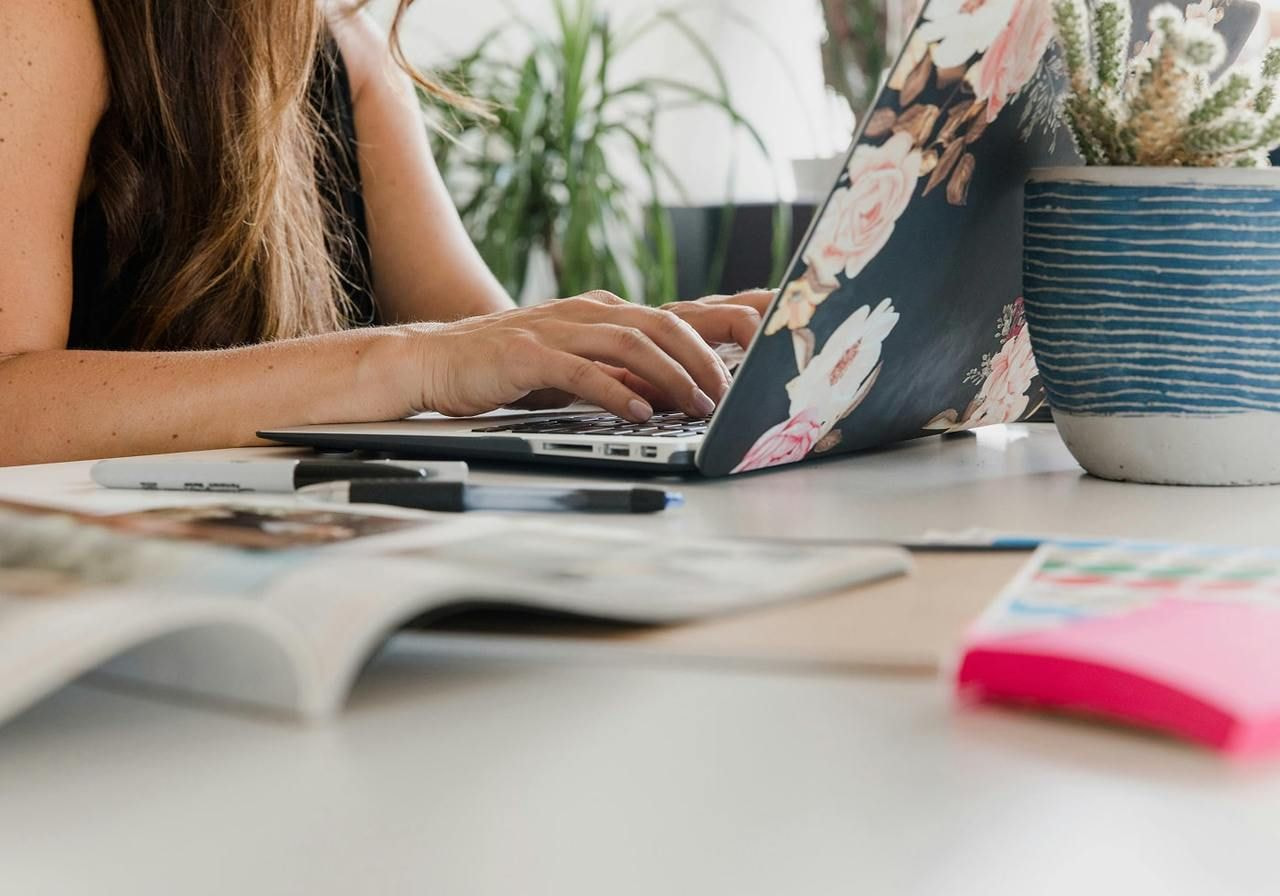 A woman sitting at a desk and typing on a laptop.